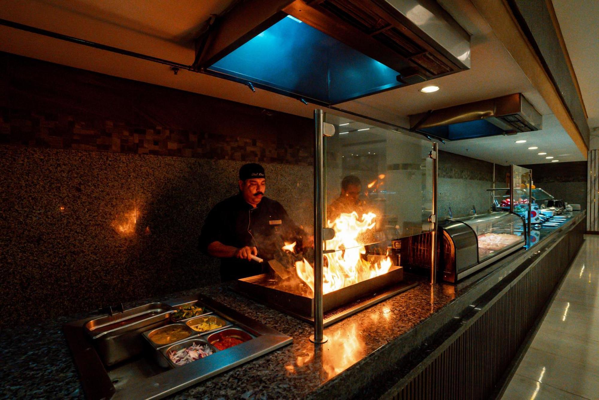 The V Luxury Resort Sahl Hasheesh Hurghada Esterno foto A chef cooking with a flaming torch