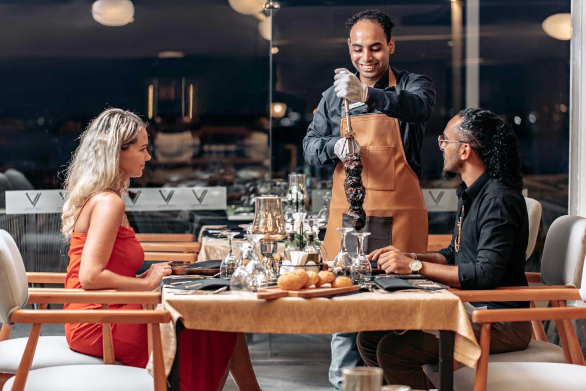 The V Luxury Resort Sahl Hasheesh Hurghada Esterno foto A waiter serving a couple at a restaurant